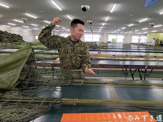 13式空挺傘を畳む工程。サスペンションライン（吊紐）を丁寧に捌き、包装の準備を整える整備中隊隊員