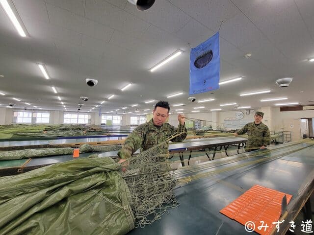 落下傘を折り畳む際、サスペンションラインに一定のテンションをかけ、正確に整列させる整備中隊員の作業風景