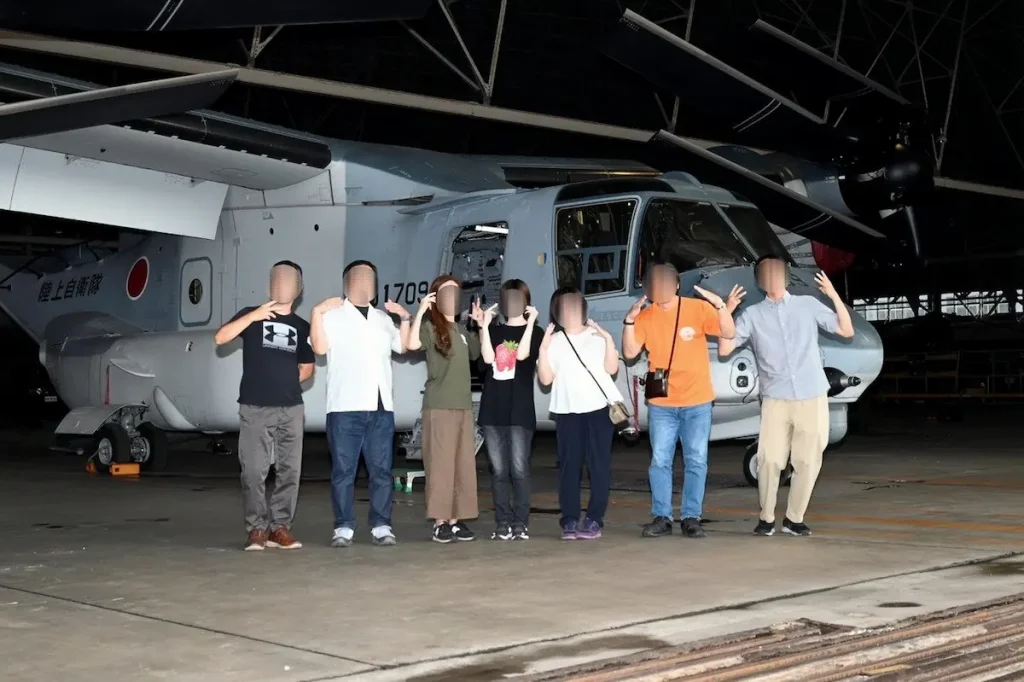 木更津駐屯地の格納庫にて、陸上自衛隊の輸送機V-22オスプレイを背景に撮影した記念写真。防衛モニターとしての部隊見学の記録
