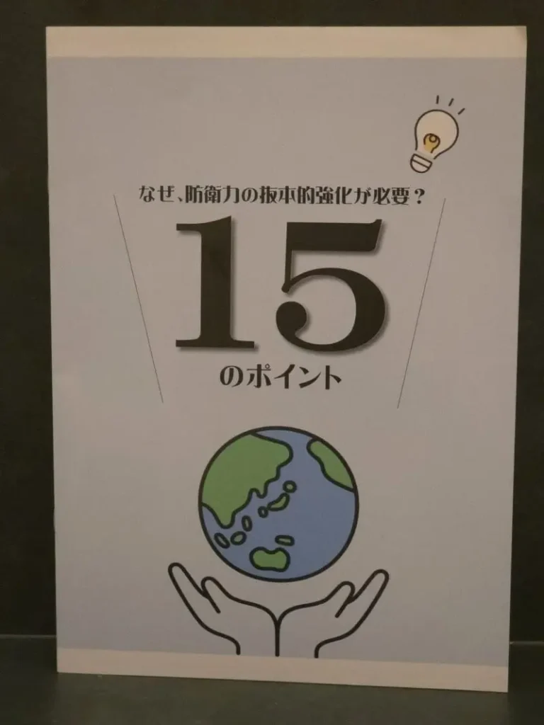 地球を包み込む手のイラストが描かれた冊子「なぜ、防衛力の抜本的強化が必要？ 15のポイント」の表紙