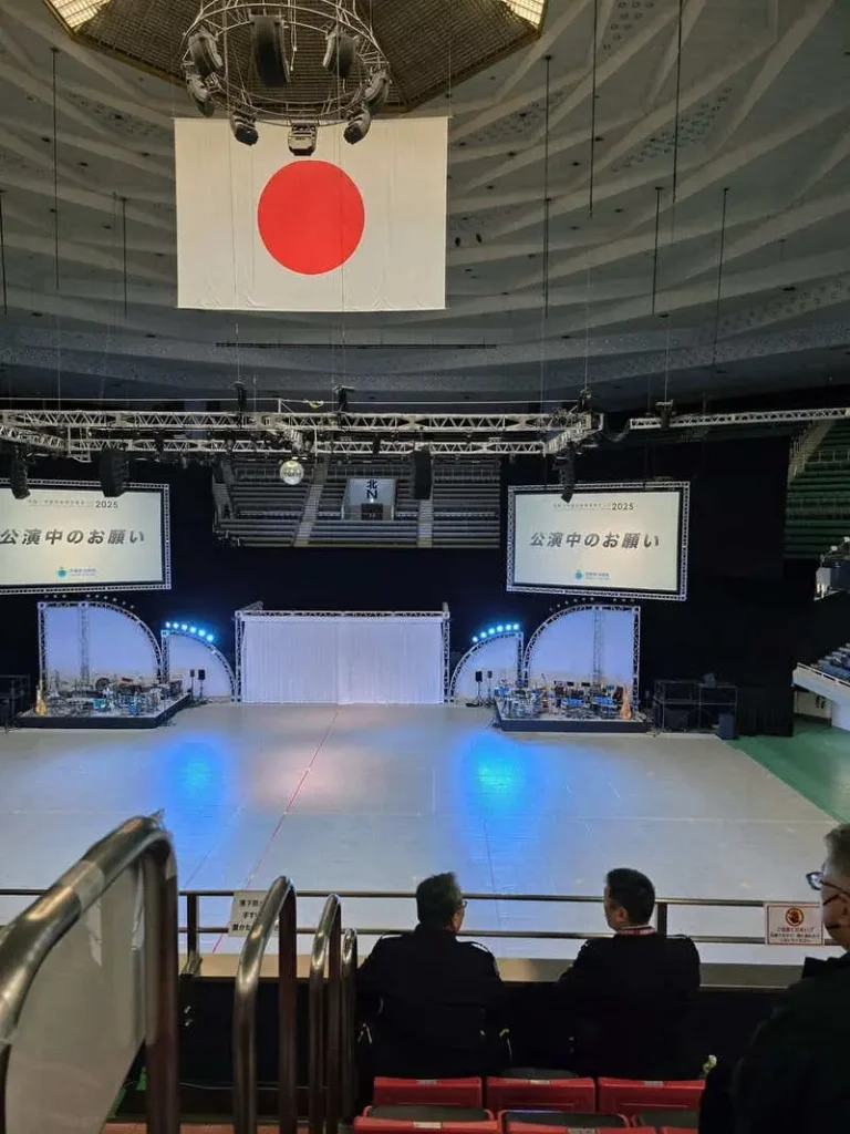 自衛隊音楽まつり2025開催中の日本武道館。正面指定席から見える、天井の大きな日の丸とステージの眺め