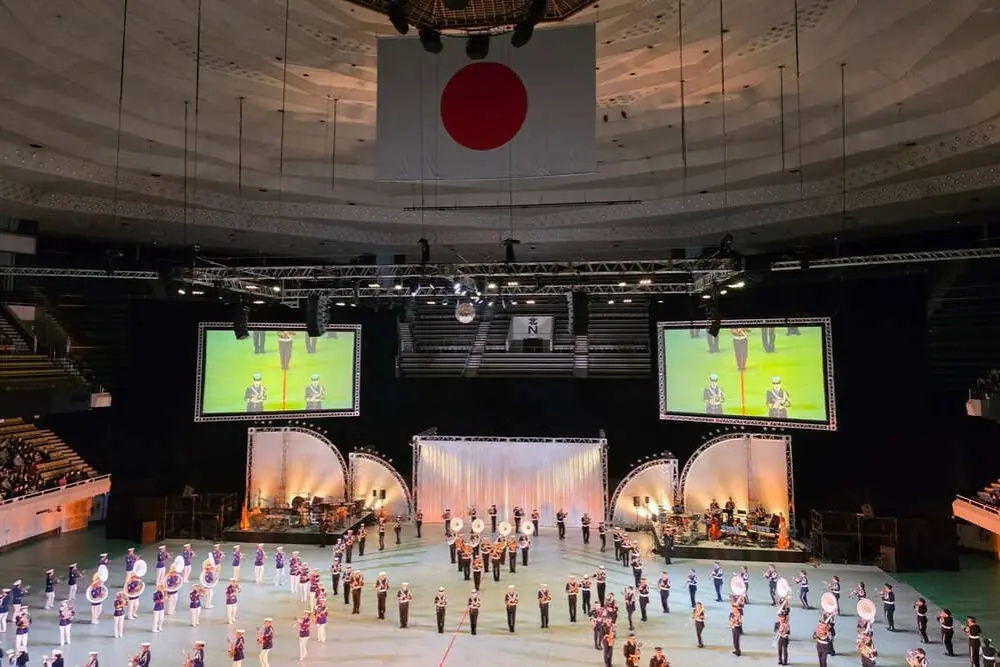 日本武道館の広いステージに陸海空自衛隊の音楽隊が整列する「自衛隊音楽まつり2025」の全景