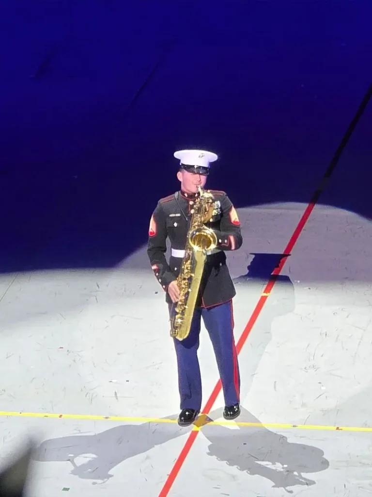 白い軍帽を被り、スポットライトの下でサックスをソロ演奏する米海兵隊の隊員